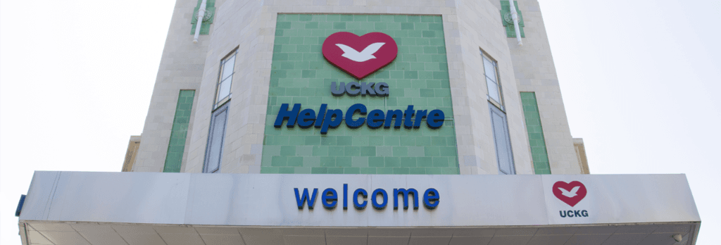 The entrance of a UCKG HelpCentre: a welcome sign beneath the UCKG HelpCentre heart-and-dove logo